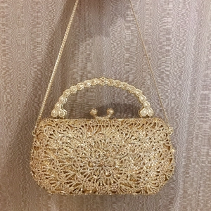 Detailed view of luxury gold evening clutch bag with sparkling rhinestones and metal handle