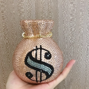 Close-up of rose gold rhinestone money bag clutch with dollar sign and gold chain strap