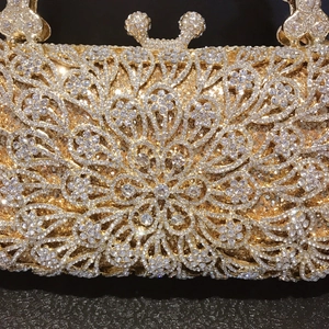 Macro detail of luxury gold floral evening clutch with crystals and ornate hollow pattern