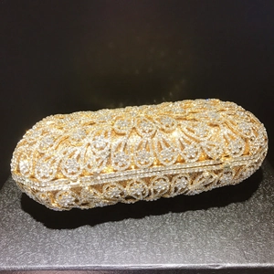Detail of gold evening clutch featuring intricate metal hollow floral patterns and rhinestones