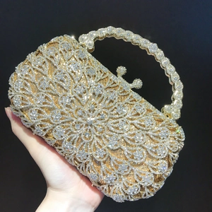 Detail of gold evening clutch with hollow floral pattern and crystal inlaid hard handle