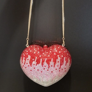 Close-up of heart-shaped evening bag with gradient rhinestones and gold chain strap