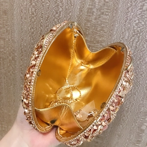 Detail view of heart-shaped evening clutch with champagne rhinestones and gold chain strap