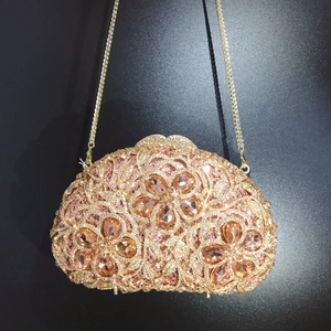 Detail of luxury champagne gold evening clutch featuring pink rhinestone floral patterns
