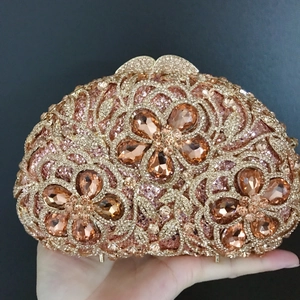 Detail of luxury rose gold evening clutch with hollowed floral design and amber crystals