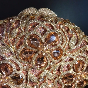 Macro shot of luxury evening bag featuring champagne gold sequins and intricate crystal flower