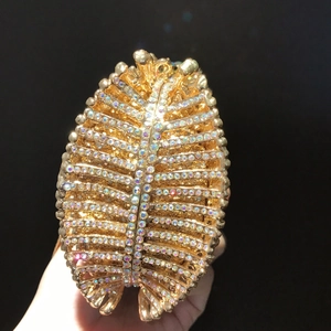 Dettaglio borsa da sera dorata con strass iridescenti e design a piuma scintillante