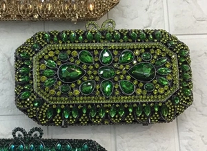 Detail showing green crystals and bow clasp on a luxury evening clutch bag