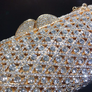 Detailaufnahme der goldenen Abendtasche mit filigranem Metallnetz und funkelnden Kristallen