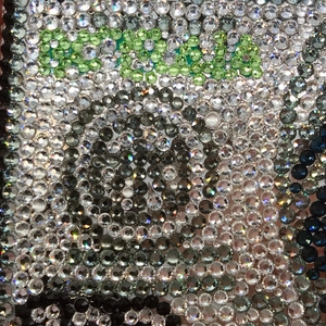 Close-up of handmade dollar clutch with green and clear rhinestones detail