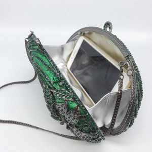 Detail of emerald green rhinestone evening clutch showing interior phone storage and chain
