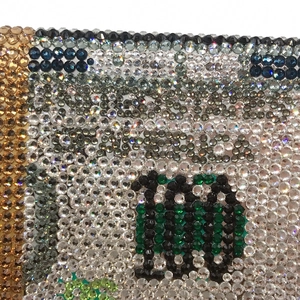 Detailed macro view of the sparkling rhinestone dollar pattern on a luxury clutch bag