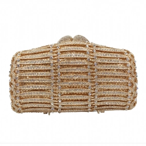Close-up of gold hollow metal frame with wavy crystal grid and heart clasp on luxury clutch
