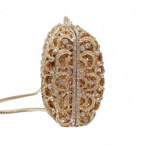 Detailed side view of golden luxury evening clutch with hollow metal and crystals