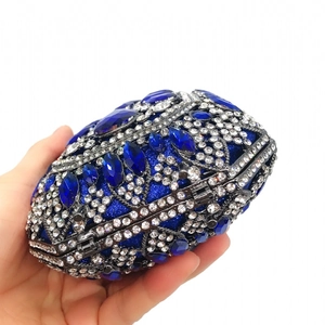 Dettaglio di una lussuosa borsa da sera con strass blu navy tenuta in mano da una donna