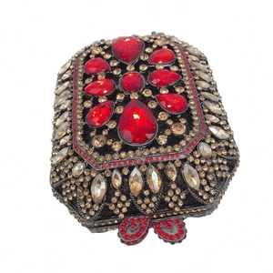 Dettaglio del motivo floreale in cristallo rosso e strass dorati sulla pochette nera da sera