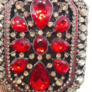 Dettaglio macro di borsa da sera con cristalli rossi a goccia e strass color champagne