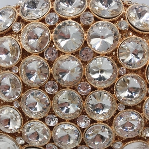 Detailed view of hollow metal evening bag with clear crystals in gold-tone claw settings