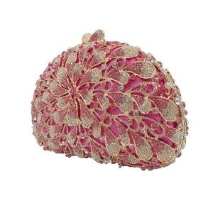 Detail of hollow gold metal pattern with pink rhinestones on rose red clutch bag