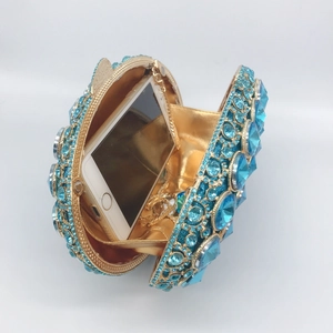 Round gold hollow crystal evening clutch with blue rhinestones and phone for size comparison