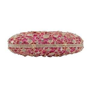 Close-up of luxury rose pink rhinestone clutch bag with gold hollowed metal frame