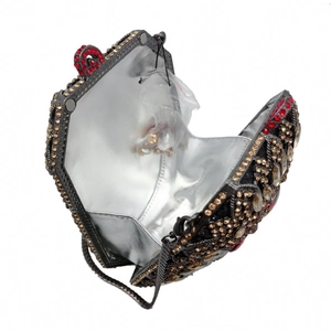 Dettagli interni di una pochette di lusso in strass rossi e oro con fodera in metallo argento
