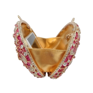 Detail of luxury gold evening bag showing pink rhinestone inlay and smartphone storage space