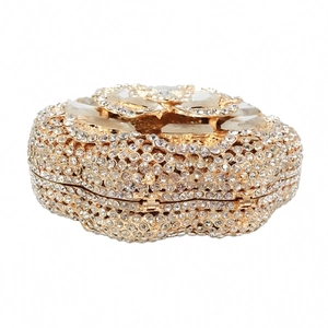 Close-up of heart-shaped gold evening clutch with sparkling rhinestones and metal hinges