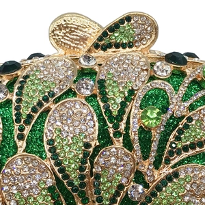 Close-up of luxury evening clutch with green and white rhinestones on gold metal frame