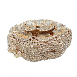 Detail of gold evening clutch featuring sparkling white rhinestones and crystal flower top