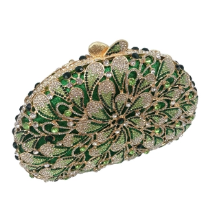 Detailed macro of hollow gold metal floral pattern with green rhinestones on evening bag