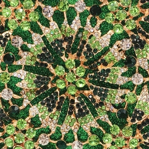 Macro detail of crystal floral clutch with green rhinestones and gold metal frame