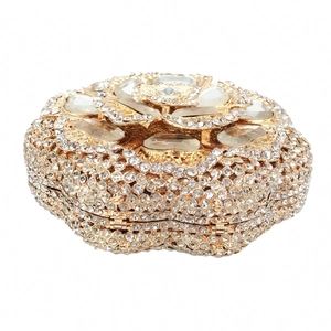 Detailed macro shot of hollow gold flower clutch bag with shimmering crystals and gems