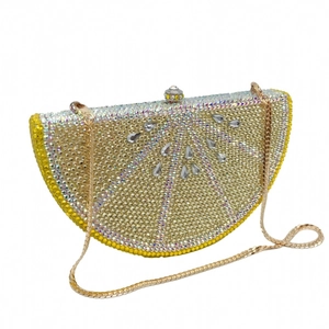 Detailed view of lemon-shaped crystal clutch bag with yellow rhinestones and gold chain
