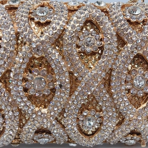 Macro view of gold metal evening bag featuring intricate crystal and diamond patterns
