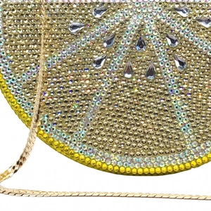 Detail of lemon wedge evening clutch bag featuring dense yellow and green rhinestones