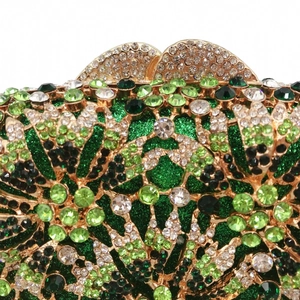 Macro detail of emerald green rhinestones and floral pattern on gold evening clutch