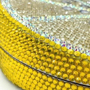 Macro detail of hand-set yellow crystals on lemon-shaped evening clutch bag