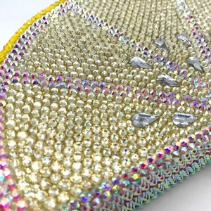 Macro detail of high-density rhinestone inlay and teardrop crystals on a lemon clutch