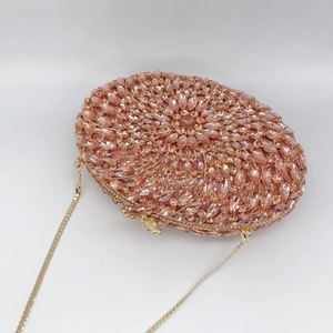 Rose gold oval evening bag with sunburst rhinestone pattern and golden chain strap