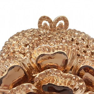 Detail of luxury evening clutch featuring hollow metal base and heart-shaped amber crystals