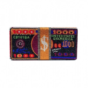 Gros plan d'une pochette motif billet 1000 dollars ornée de strass multicolores brillants