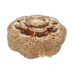 Macro detail of gold flower clutch bag featuring sparkling rhinestones and brown crystals
