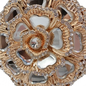 Macro detail of luxury floral evening clutch showing golden metal petals and inlaid crystal