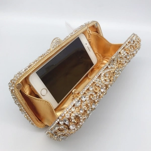Detail of gold hollow evening clutch showing rhinestone scroll pattern and phone storage