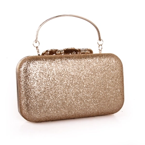 Close-up of golden glitter evening clutch with rhinestone bow clasp and metal handle