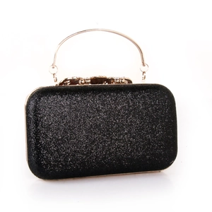 Detail of black glitter evening clutch featuring a gold metal handle and rhinestone clasp