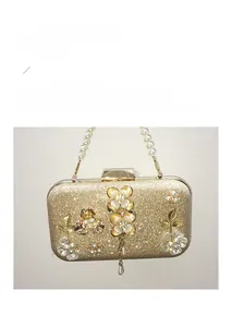 Détail de la pochette de soirée dorée avec poignée en perles et ornements de fleurs