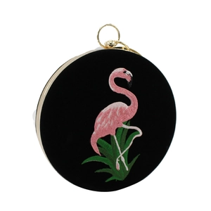 Detail van flamingo borduurwerk op een ronde avondtas van zwart fluweel