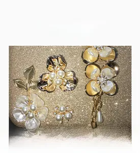 Détails des fleurs en perles et feuilles métalliques sur pochette dorée scintillante
